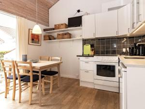 a kitchen with white cabinets and a table and chairs at 4 person holiday home in r sk bing in Ærøskøbing