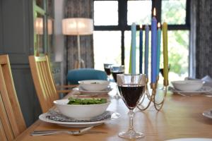a table with a glass of wine and a bowl of greens at Badminton, Thorpeness in Thorpeness