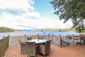 a table and chairs on a deck next to a body of water at Lakeside Lodge in Windermere