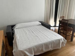 a bed with a white comforter in a room at Apartamentos Redondela - Centro histórico in Redondela