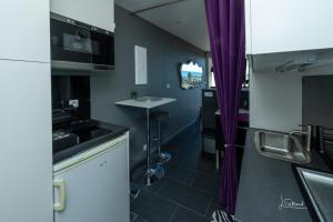 uma cozinha com cortinas roxas e um lavatório em Studio Glamour Naturiste em Cap d'Agde
