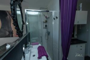 y baño con lavabo y ducha con cortinas moradas. en Studio Glamour Naturiste, en Cap d'Agde