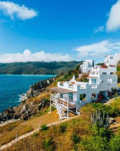 una casa blanca en una colina junto al agua en Casa Grega, en Arraial do Cabo