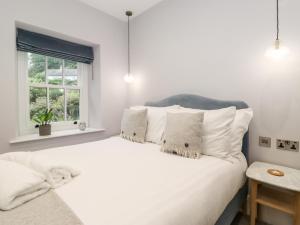 a white bedroom with a large white bed with pillows at Eller Close House in Ambleside