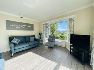 a living room with a couch and a tv and a window at Three Peaks in Braithwaite