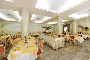 a restaurant with white tables and chairs and tablesearcher at Hotel Terme Patria in Abano Terme