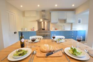 a kitchen with a wooden table with plates of food and wine at Somewhere Only We Know, Aldeburgh in Aldeburgh