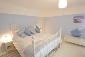 a bedroom with a white bed with blue pillows at Somewhere Only We Know, Aldeburgh in Aldeburgh