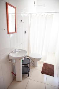 uma casa de banho branca com um lavatório e um WC em Oca Delfim em Delfim Moreira