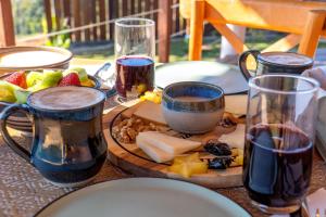 uma mesa coberta com taças de vinho e queijo em Atiaia Jungle River Retreat em Visconde de Mauá