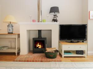 a living room with a fireplace and a tv at The Roost in Cheriton