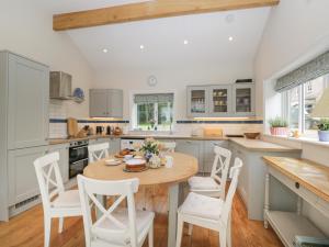 a kitchen with a wooden table and white chairs at The Roost in Cheriton