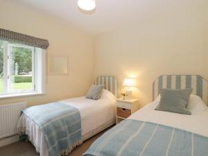 two beds in a small bedroom with a window at The Roost in Cheriton