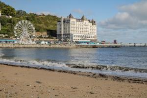 a beach with a large building and a ferris wheel at Dolphin Court in Colwyn Bay