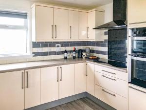 a white kitchen with white cabinets and a window at Ballygroggan Bungalow - Uk38174 in Machrihanish