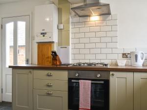 uma cozinha com um fogão e um fogão forno superior em Peppercorn Cottage em Enderby