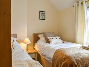 um quarto com duas camas e um candeeiro sobre uma mesa em Peppercorn Cottage em Enderby