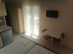 a living room with a table and chairs and a television at KALIPSO STUDIOs in Nikiti