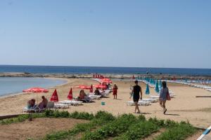 un gruppo di persone su una spiaggia con ombrelloni di Livana Hotel a Ayia Trias
