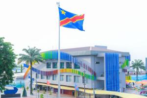 eine Flagge vor einem Gebäude mit Pool in der Unterkunft AQUA INN Hotel in Kinshasa