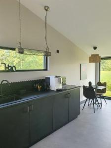 uma cozinha com armários verdes e uma mesa com cadeiras em Hippe Schuur em Tietjerk