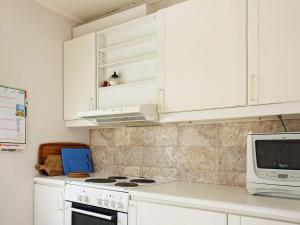 a kitchen with white cabinets and a stove and a microwave at 8 person holiday home in STRÖMSTAD in Strömstad