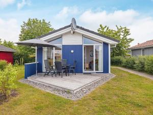 una casita azul con terraza y sombrilla en 4 person holiday home in GROEMITZ, en Grömitz