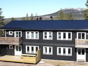 una casa negra con techo azul y terraza en Apartment SÄLEN II, en Stöten