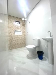 a white bathroom with a toilet and a sink at Hotel Praça da Árvore in Sao Paulo