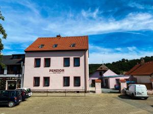 a building with a red roof in a parking lot at Penzion Český Dvůr in Starý Plzenec