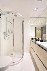 La salle de bains blanche est pourvue d'une douche et d'un lavabo. dans l'établissement Marine Hotel apartament prywatny studio widok na morze basen sauna jacuzzi 5 piętro, à Kołobrzeg