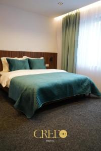 a bedroom with a large bed with a green blanket at Hotel Credo in Prizren