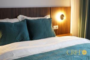 Cama con sábanas y almohadas verdes y blancas en Hotel Credo en Prizren