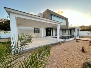 a large white house with a palm tree in front of it at Tush villa is a new, spacious, modern, cheerful in Calodyne