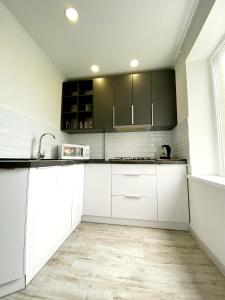 uma cozinha com armários brancos e um lavatório em Стильная квартира в светлых тонах em Dnipro