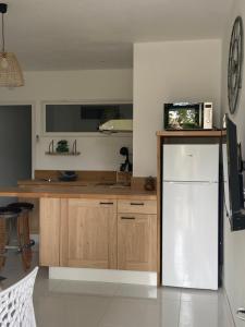 een keuken met een witte koelkast en houten kasten bij Le p'tit mandarinier in Canet d'Aude