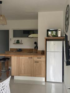 cocina con nevera blanca y armarios de madera en Le p'tit mandarinier, en Canet d'Aude