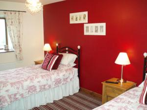 a bedroom with red walls and two beds in it at Foxhill Barn in Gisburn