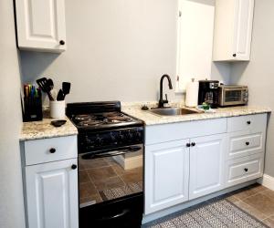 a kitchen with white cabinets and a stove and a sink at Lovely One Bedroom home/ guest house in Lakeland