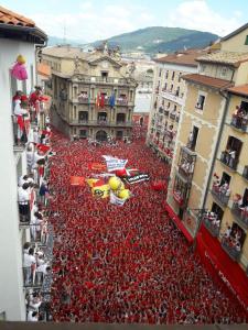 a large group of people in red shirts in a street at Atico en la Plaza del ayuntamiento in Pamplona