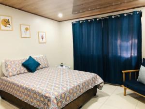 1 dormitorio con cama y cortina azul en Departamento H González 2, en El Coco