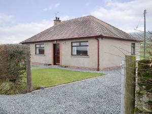 a house with a gravel driveway in front of it at Beuchan Bungalow in Closeburn