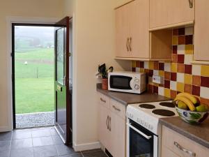 a kitchen with a microwave and a stove top oven at Beuchan Bungalow in Closeburn