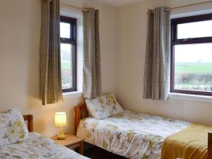 a bedroom with two beds and two windows at Beuchan Bungalow in Closeburn