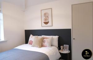 1 dormitorio con 1 cama con almohadas rosas y blancas en Bee Stays - Caldecott House en Mánchester