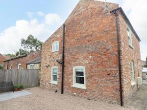 a brick building with white windows and a fence at Printers Cottage in Alford