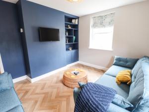 a living room with a blue couch and a tv at Printers Cottage in Alford