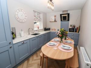a kitchen with blue cabinets and a wooden table at Printers Cottage in Alford
