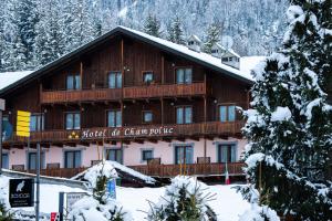 een groot houten gebouw met een bord in de sneeuw bij Hotel De Champoluc in Champoluc