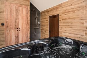 a bathroom with a black tub and a shower at Villa Inverno & Spa in Kolašin